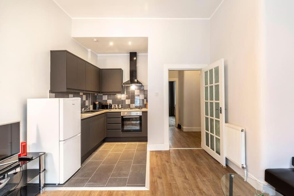 a kitchen with a white refrigerator and wooden floors at Stunning Ground Floor flat in Southside. in Glasgow