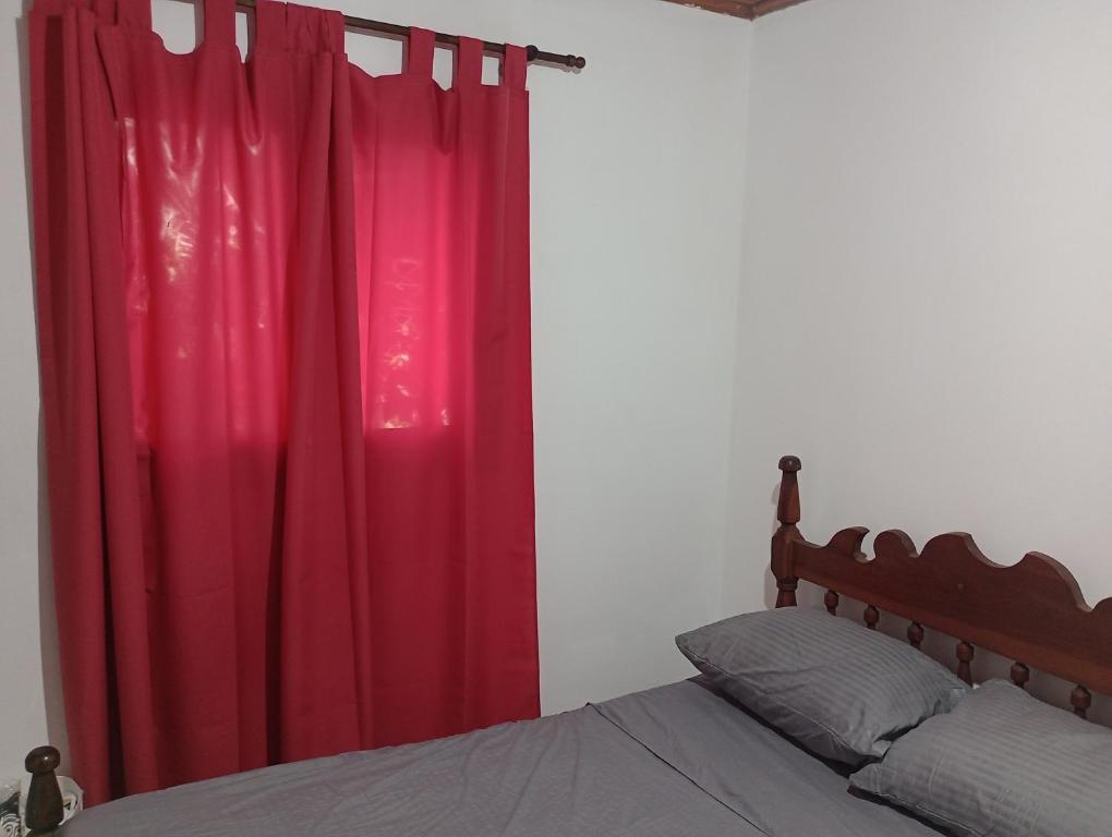 1 dormitorio con cortina roja y cama en Casona el ancla en Eldorado
