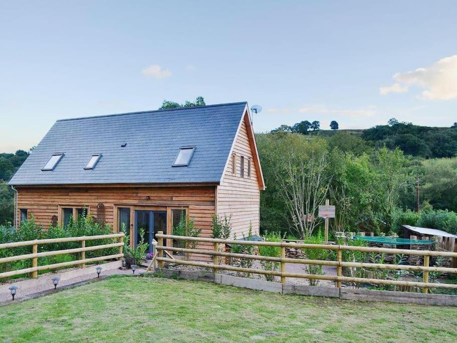 a wooden barn with a fence in front of it at ‘The Little House on The Priory’ with Hot Tub in Abergavenny