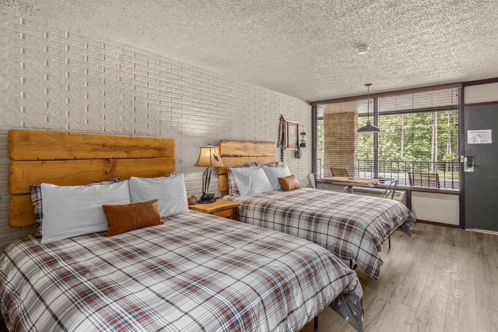 a bedroom with two beds and a desk and a window at Stonegate Lodge 2 Queen Beds WIFI TV Salt Water Pool Fire Pits #303 in Eureka Springs