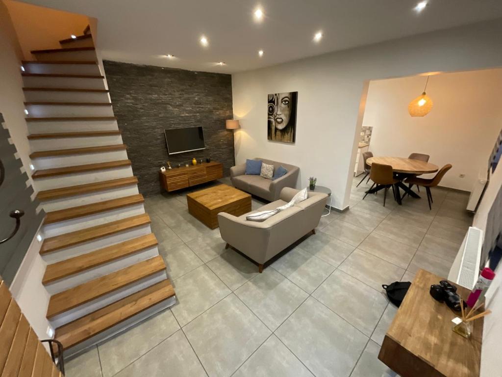 a living room with a staircase and a couch and a table at Maison 3 chambres proximité aéroport et grand axes in Charleroi