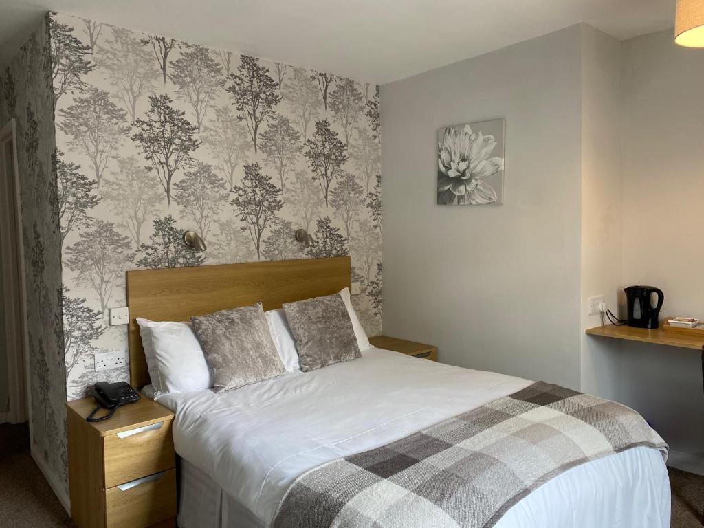 a bedroom with a bed and a wall with floral wallpaper at The Granby Inn in Longframlington