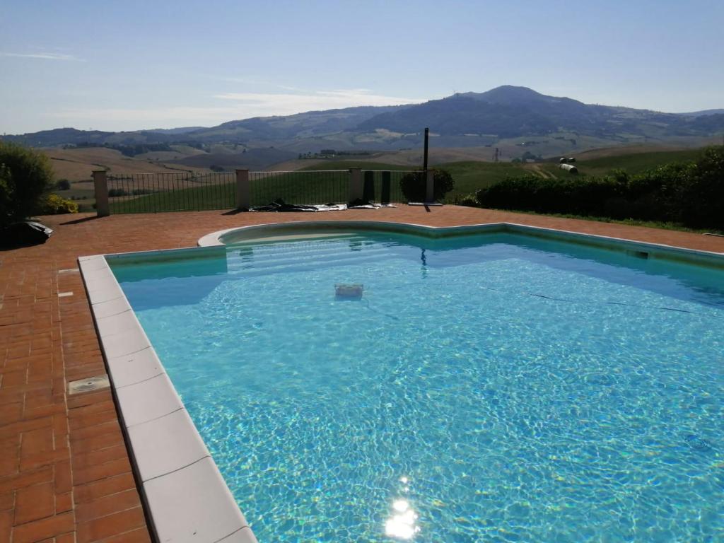 a large blue swimming pool with mountains in the background at Podere le Volpaie in Montecatini Val di Cecina