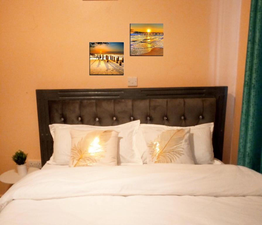 una camera con un letto bianco con due immagini sul muro di T-Tree Paradise Apartments a Embu