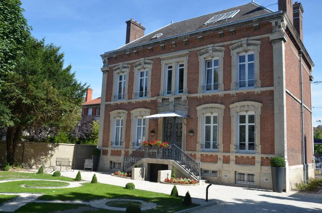 Un grand bâtiment en briques avec un escalier se trouve devant. dans l'établissement La Demeure De Charme, à Troyes