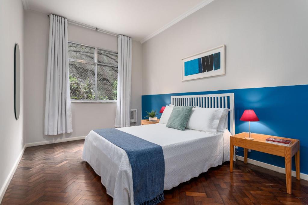 um quarto com uma cama e uma parede azul em 2 Quartos - Amplo e confortável perto do Metro Flamengo no Rio de Janeiro