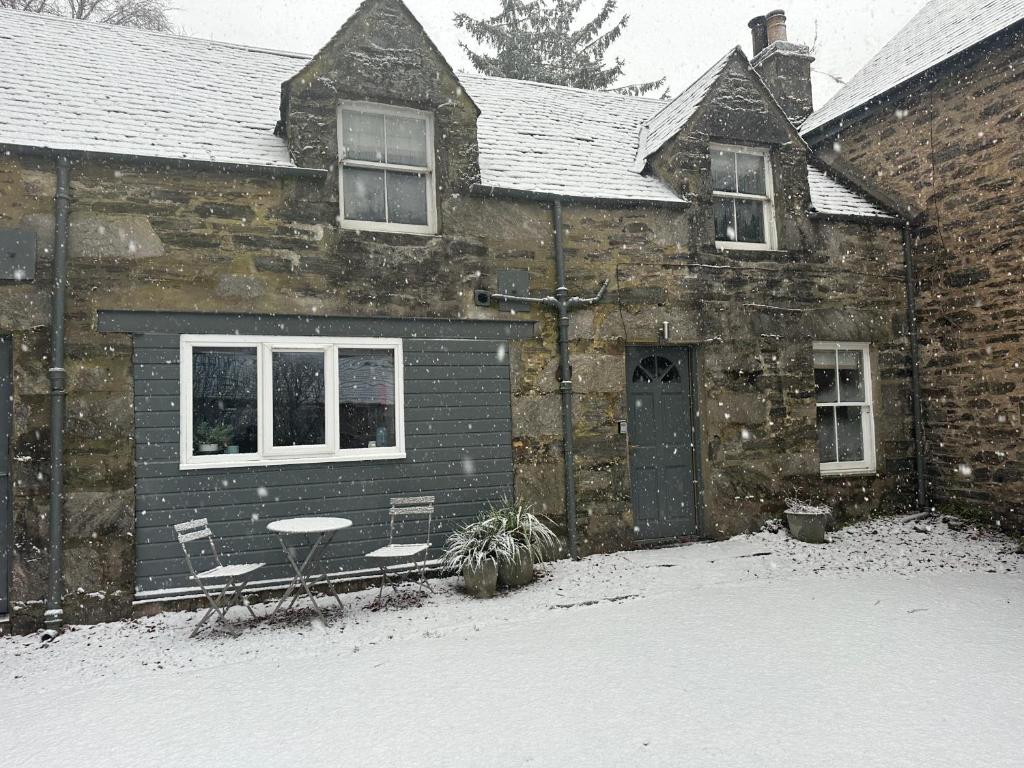 una casa con mesa y sillas en la nieve en Red Squirrel Cottage, en Strathtay