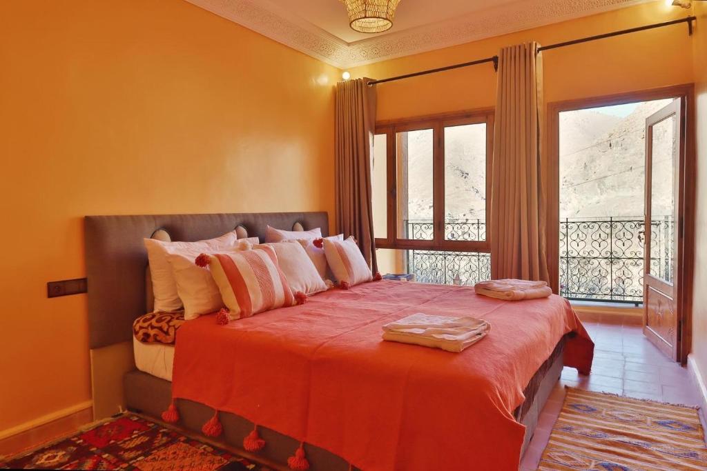 a bedroom with a bed with orange walls and a window at La Perle de Neige in Imlil
