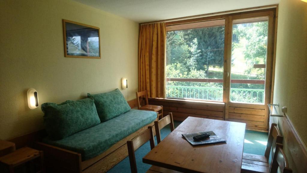 un salon avec un canapé, une table et une fenêtre dans l'établissement Résidence Lauzieres - Studio 5 personnes skis aux pieds et proche des commerces dans le village du Charvet à Arc 1800 MAE-1752, à Arc 1800