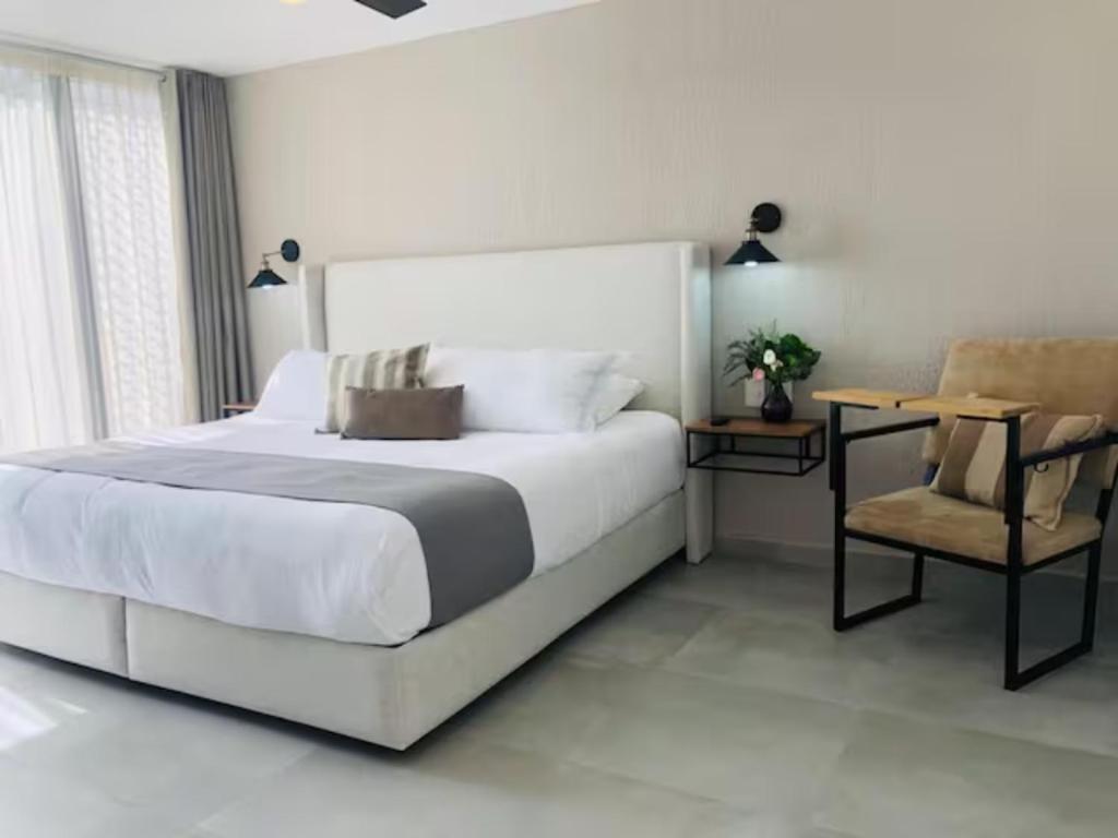 a white bedroom with a large bed and a chair at Urban Chapalita in Guadalajara