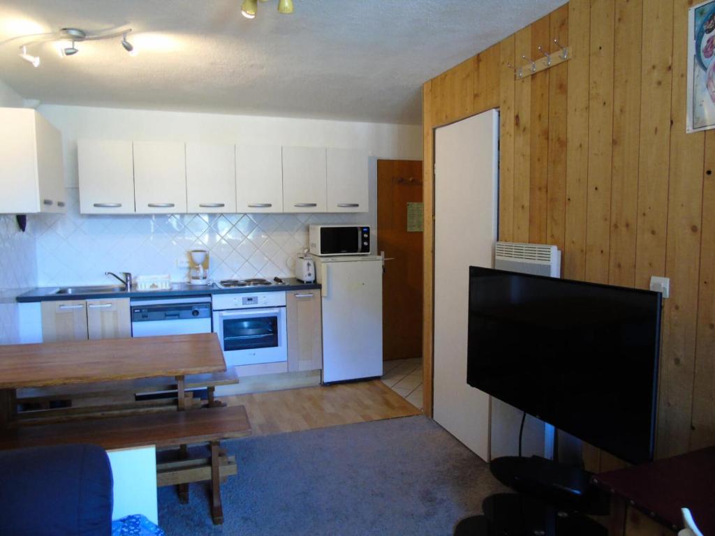 une cuisine avec des appareils électroménagers blancs et une table avec une télévision dans l'établissement Résidence Thabor - 3 Pièces pour 6 Personnes MAE-8724, à Modane