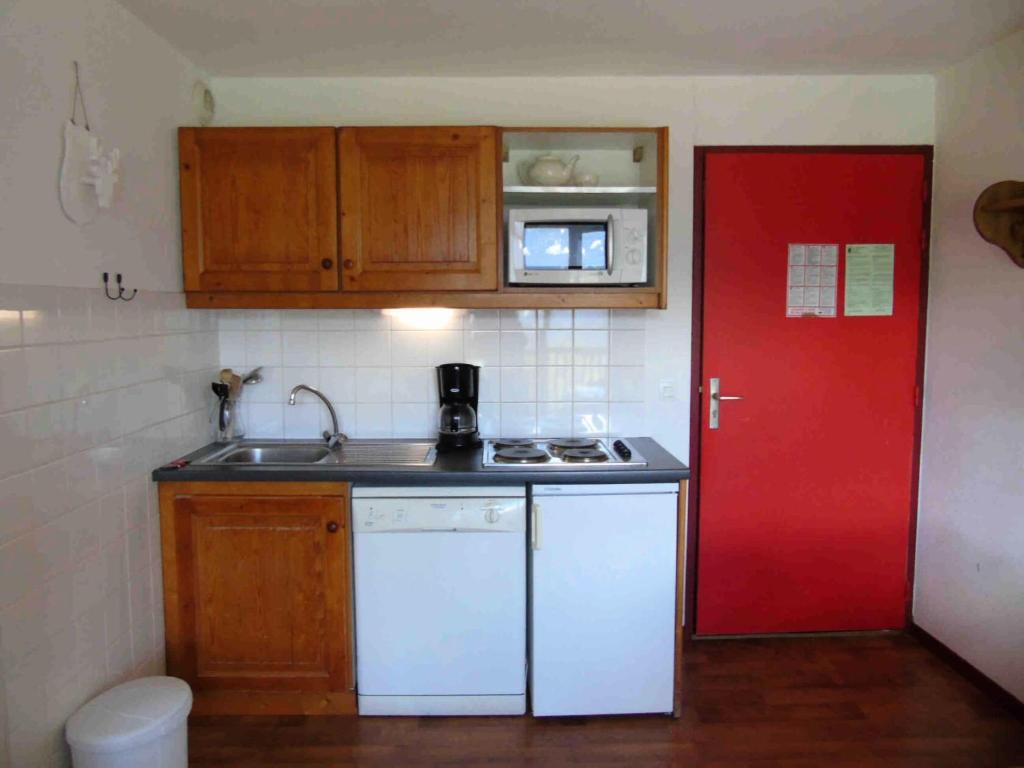 - une petite cuisine avec une porte rouge et un comptoir dans l'établissement Résidence Cheval Blanc - 2 Pièces pour 4 Personnes MAE-8824, à Modane