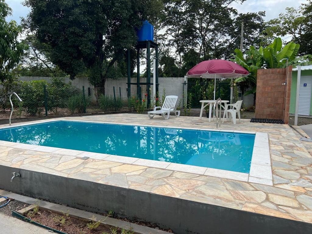 a swimming pool with a table and an umbrella at Pousada Encanto das águas in Águas de São Pedro