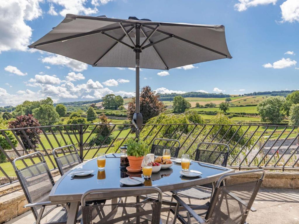 einen Tisch mit einem Sonnenschirm auf einer Terrasse mit Aussicht in der Unterkunft 3 Bed in Ashford In The Water 88675 in Great Longstone