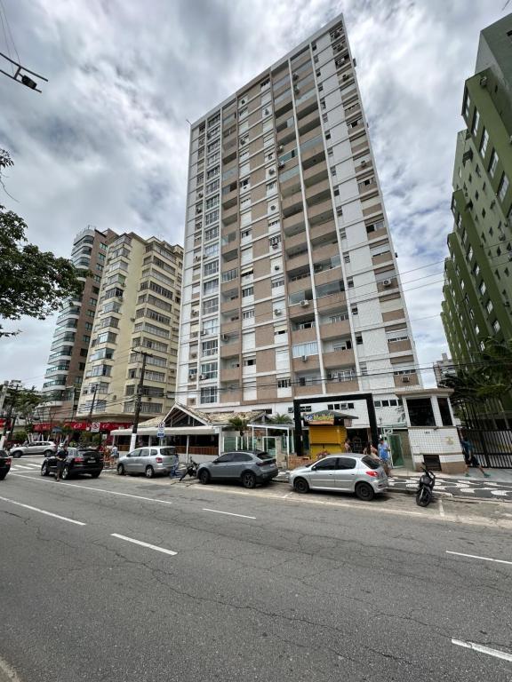 a tall building with cars parked on the side of a street at Kitnet em frente a praia de Santos in Santos
