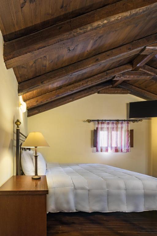 a bedroom with a white bed and wooden ceilings at Porto Kale Guesthouse in Porto Kagio