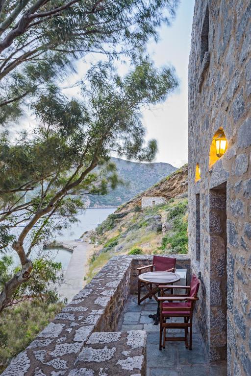a patio with two chairs and a table on a stone wall at Porto Kale Guesthouse in Porto Kagio