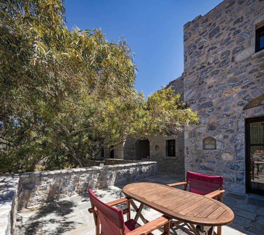 a wooden table and chairs next to a stone building at Porto Kale Guesthouse in Porto Kagio