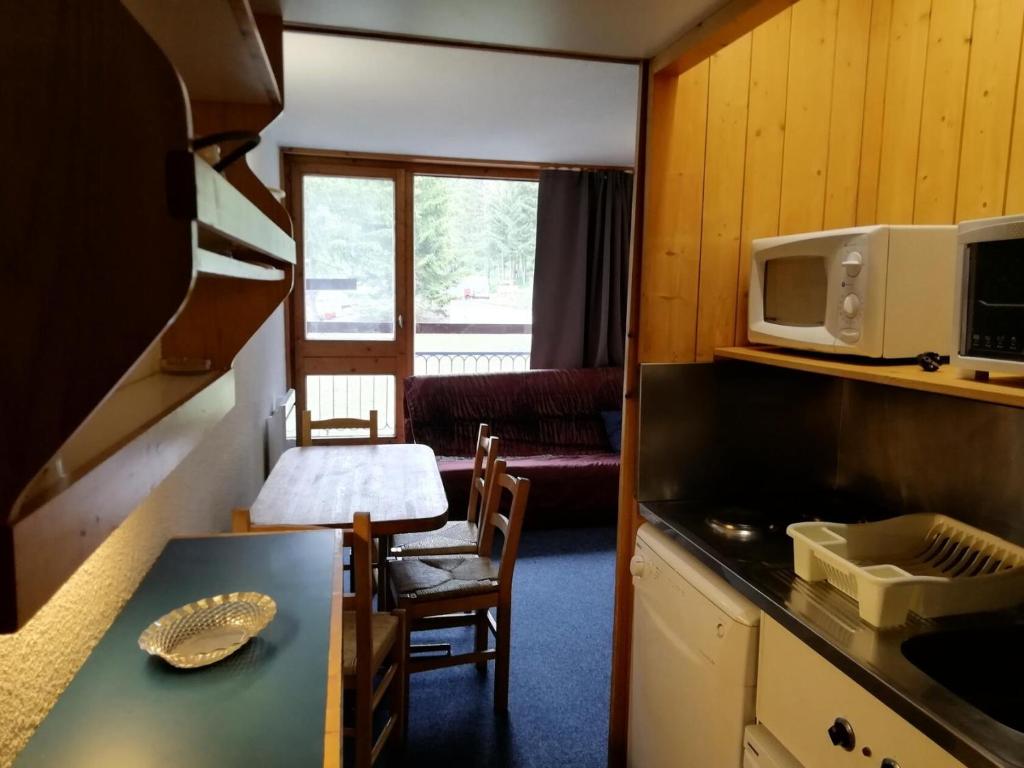 une petite cuisine avec une table et un micro-ondes dans l'établissement Résidence Belles Challes - Studio 4 personnes à Arc 1800 skis aux pieds et proche des commerces dans le village du Charvet MAE-1945, à Arc 1800