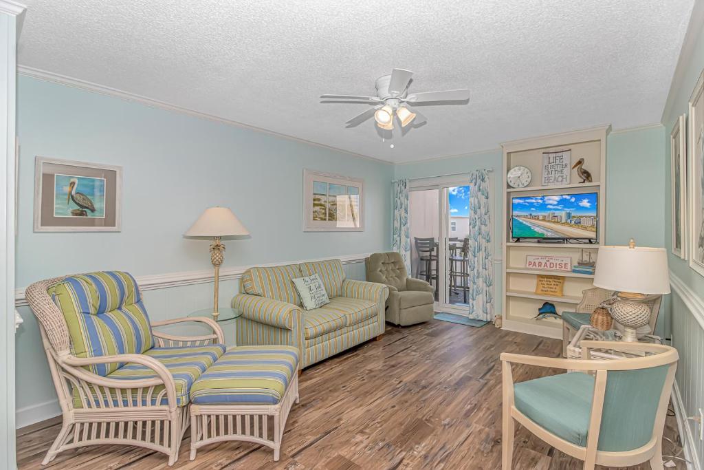 a living room with a couch and chairs and a ceiling fan at Salty Dogs - Gated, Private Dock, Beach Access in Myrtle Beach