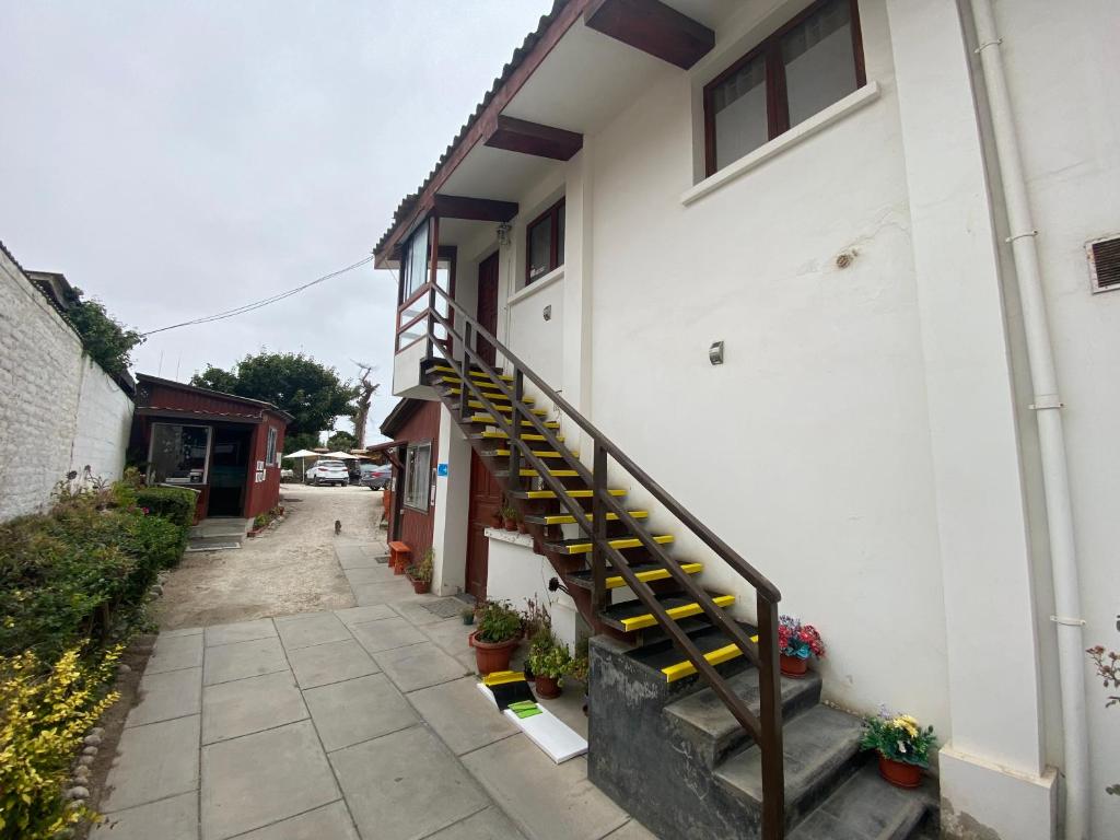 a white building with a staircase next to it at Hotel Cabañas Caribe in Los Vilos
