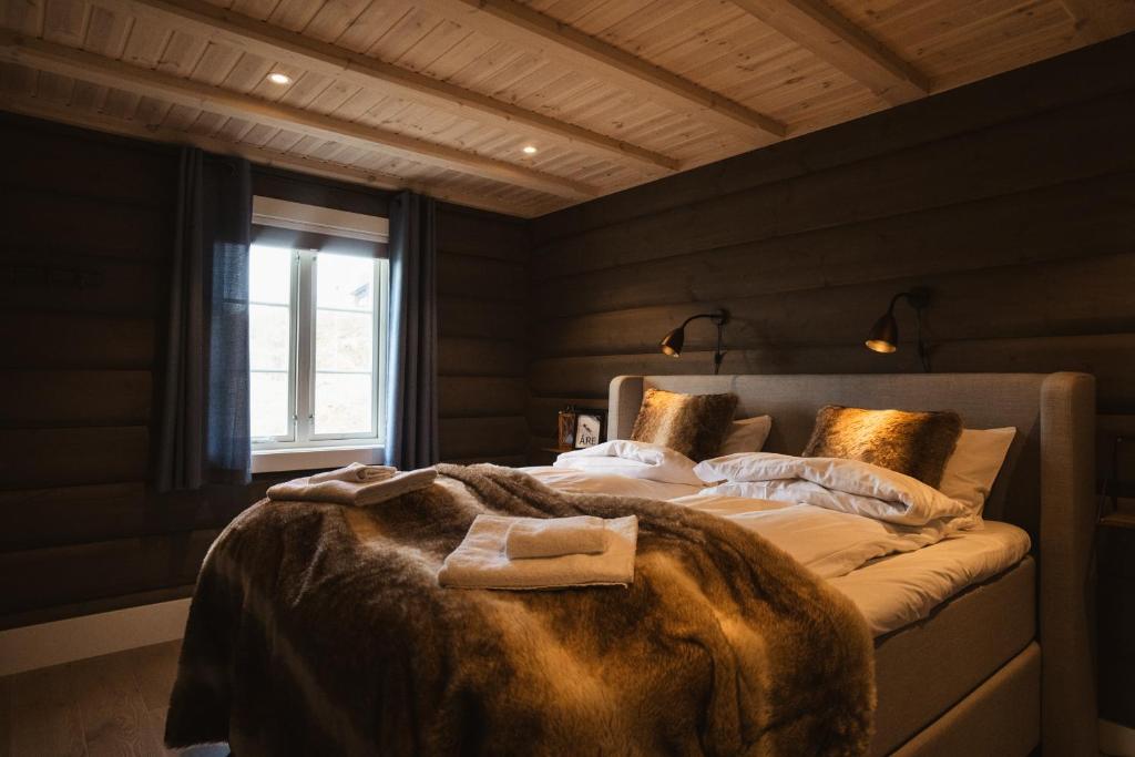a bedroom with a bed with a blanket and a window at Åre Valley Lodges - Grand Ski Lodge in Åre