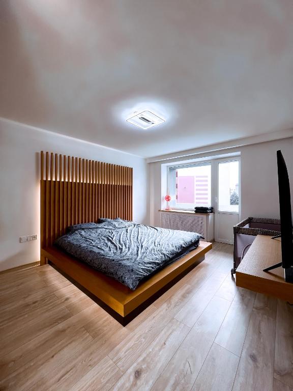 ヴェンツピルスにあるCozy Retreat Apartmentのベッドルーム1室(大型ベッド1台、木製ヘッドボード付)