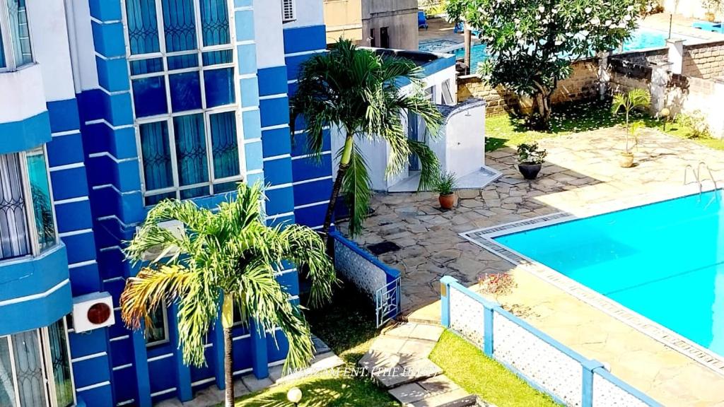 een blauw gebouw met palmbomen naast een zwembad bij Two Bedroom Nyali, City Mall in Mombasa