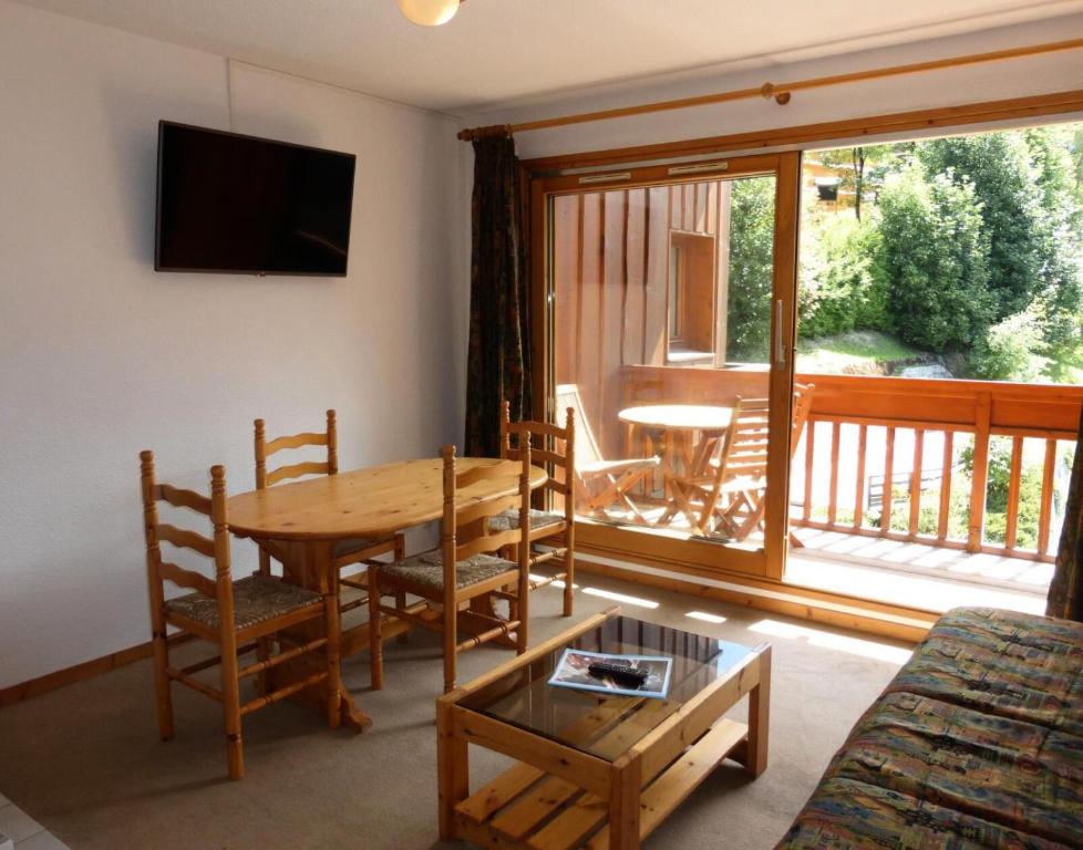 a living room with a wooden table and a balcony at Résidence Le Cristal - 2 Pièces pour 4 Personnes 34 in Les Allues