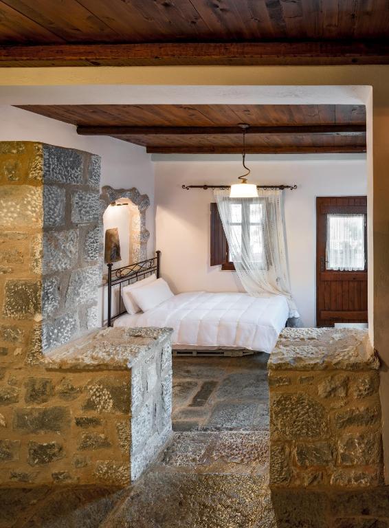 a bedroom with a bed and a stone wall at Porto Kale Guesthouse in Porto Kagio