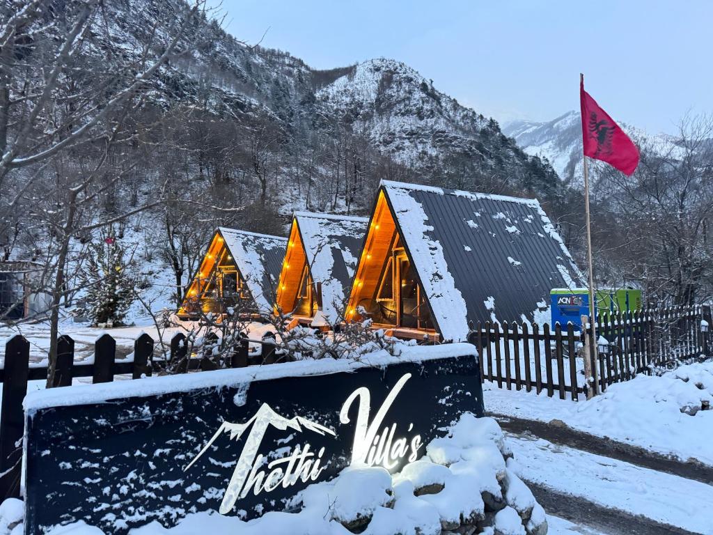 a group of lodges in the snow with a red flag at Thethi Villas in Theth