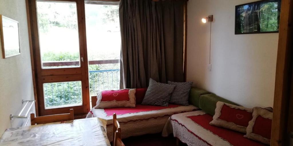 un salon avec un canapé et une fenêtre dans l'établissement Résidence Belles Challes - Studio 4 personnes à Arc 1800 skis aux pieds et proche des commerces dans le village du Charvet MAE-2200, à Arc 1800