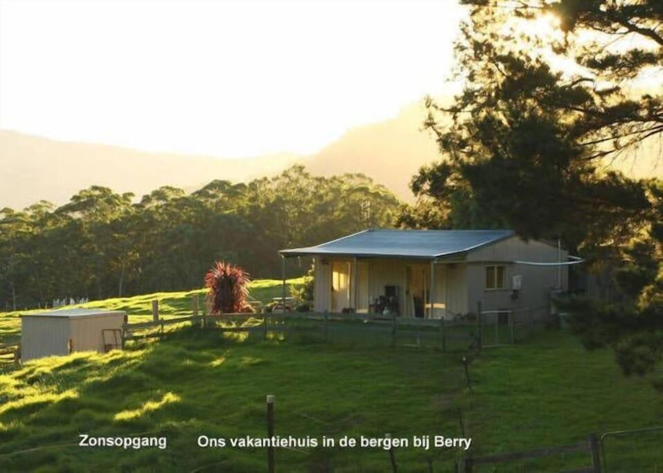 a small house on a grassy hill with a tree at Fairmont Cottage in Woodhill