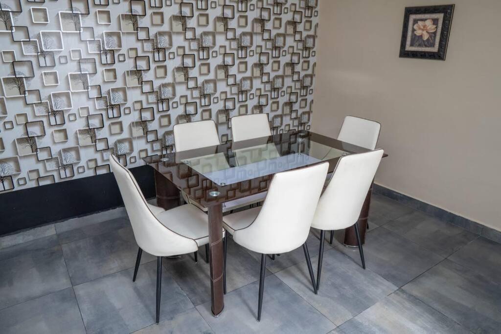 a dining room table with white chairs and a wall at Casa Magnolia in Tarija