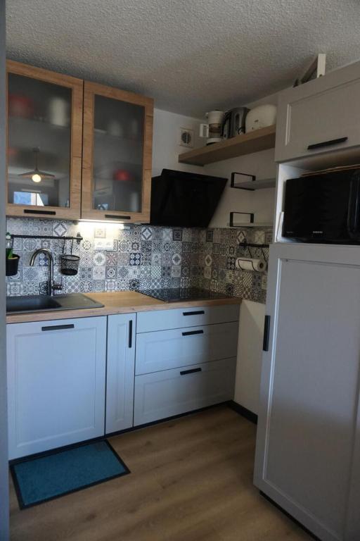 une cuisine avec des armoires blanches et un réfrigérateur blanc dans l'établissement Résidence Piniers - studio cabine 4 personnes MAE-2828, à Orcières