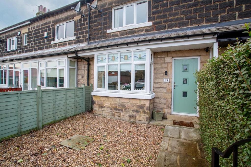 uma casa de tijolos com uma porta verde e um quintal em Stylish and cosy cottage in the heart of Yorkshire em Leeds