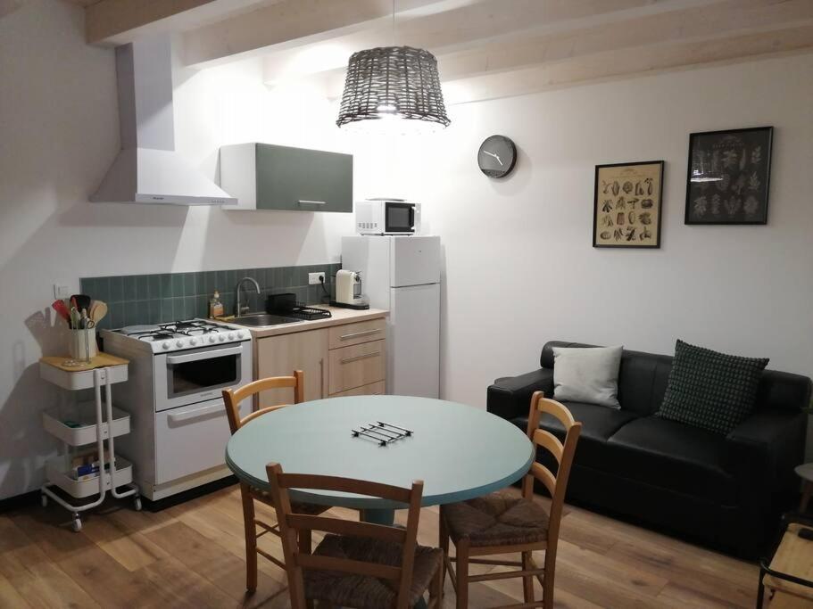 cocina y sala de estar con mesa y sofá en Studio aux Granges du Vilaret, en Clairvaux-les-Lacs