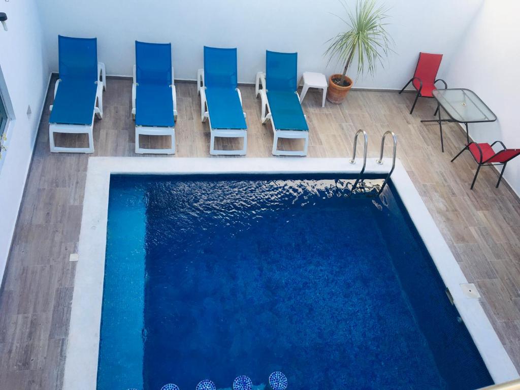 a swimming pool with blue and red chairs next to it at Casa Ohana By Utopia in Playa del Carmen