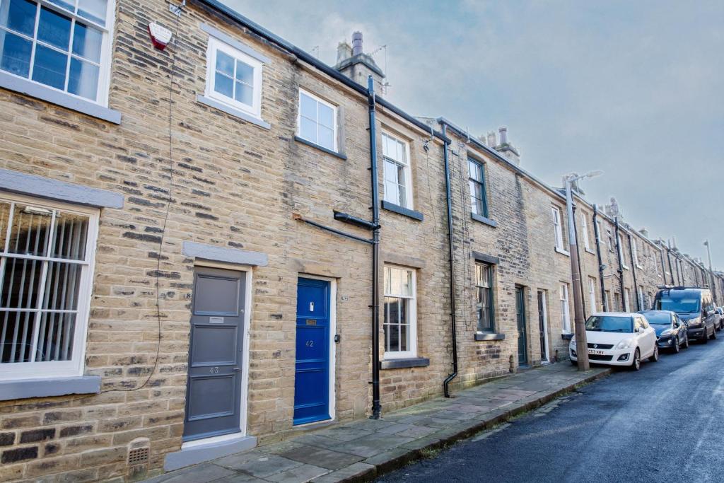 a brick building with a blue door on a street at Cosy 2 bedroom Cottage in a World Heritage Village in Shipley