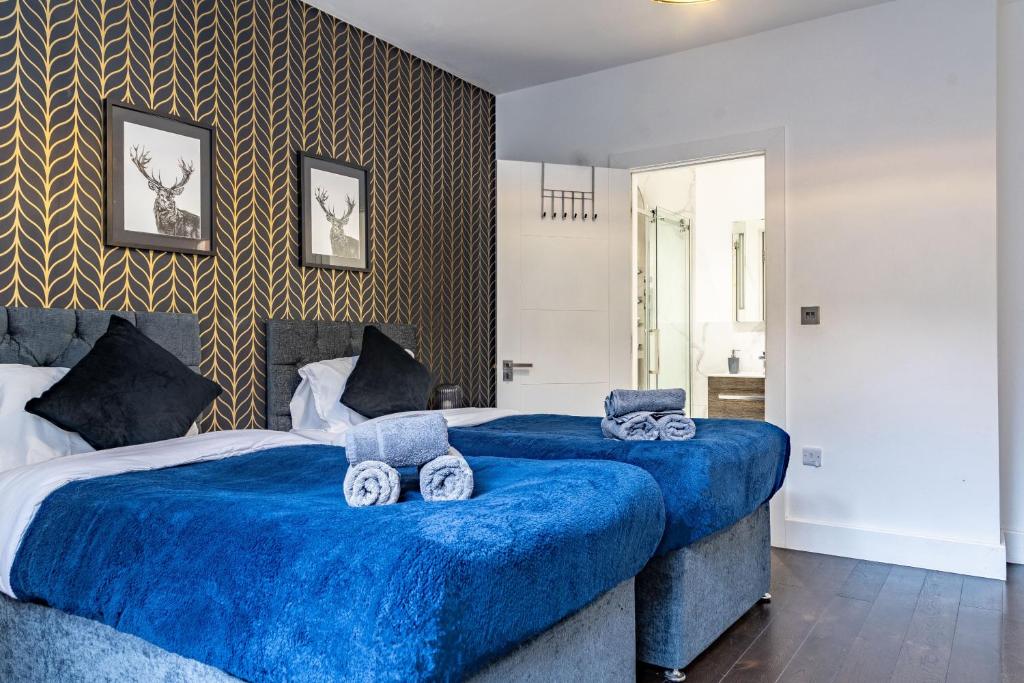 two beds in a bedroom with blue sheets at Luxurious & Spacious Apartment in Reading