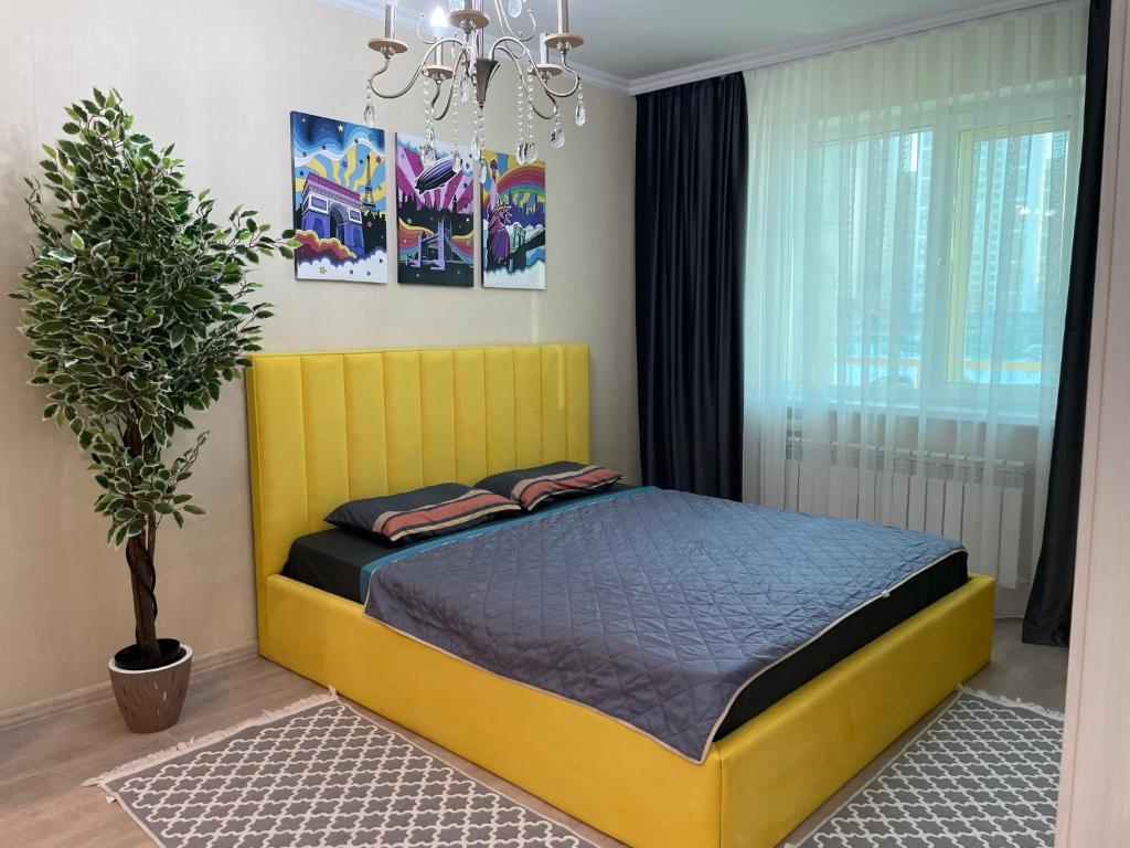 a yellow bed in a bedroom with a potted plant at Botanical Garden in Taldykolʼ