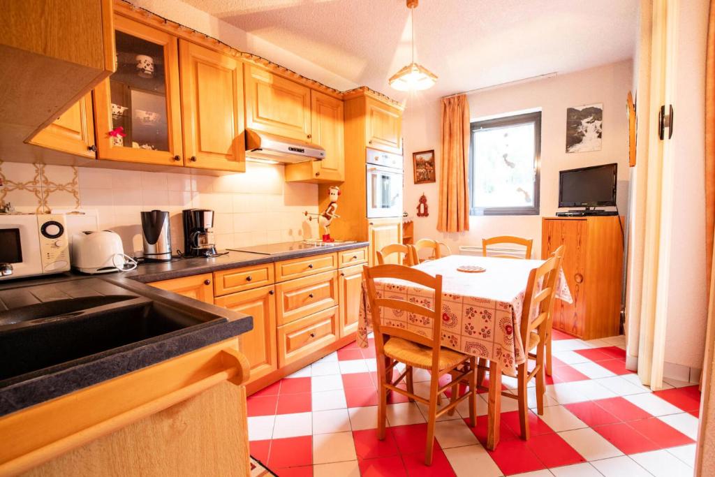 une cuisine avec des armoires en bois et une table avec des chaises dans l'établissement Résidence Les Airelles - LES AIRELLES - AI26HD MAE-3154, à Villarodin-Bourget