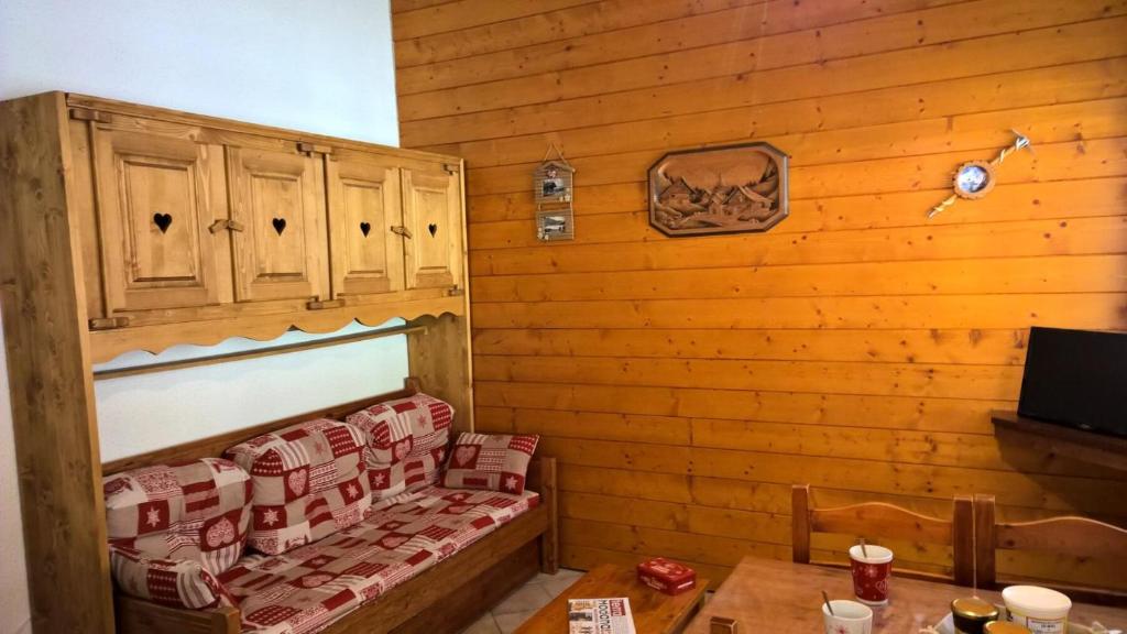 una camera con una parete in legno, un divano e un tavolo di Résidence Le Village - 2 Pièces pour 4 Personnes 193204 a Villarodin-Bourget