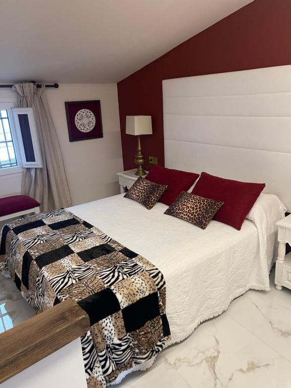Schlafzimmer mit einem großen Bett mit roten Wänden in der Unterkunft El Comercio in Villarejo del Valle