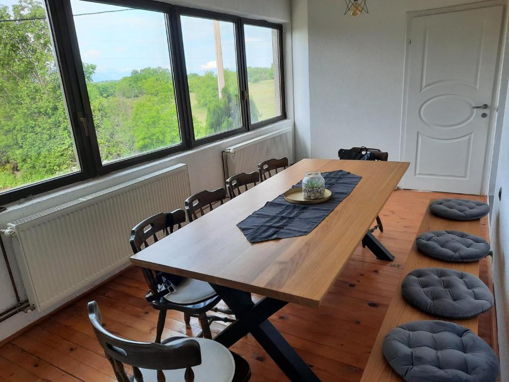 ein Esszimmer mit einem Tisch, Stühlen und Fenstern in der Unterkunft Ivković Residence in Livno