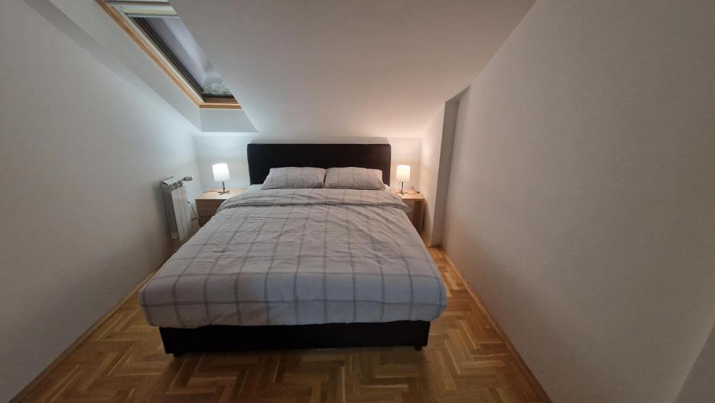 Stan na dan Apartman S في بوزاريفاتش: غرفة نوم بسرير واضاءتين على طاولتين