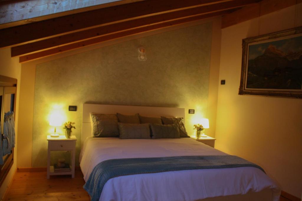 una camera con un grande letto e due lampade sui tavoli di La Casa di Malò a Piancogno