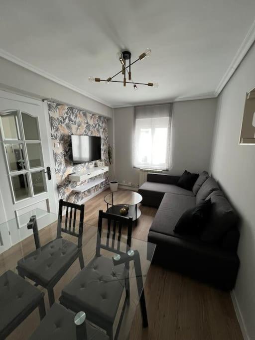 een woonkamer met een zwarte bank en stoelen bij Piso acogedor cerca del centro. in Burgos