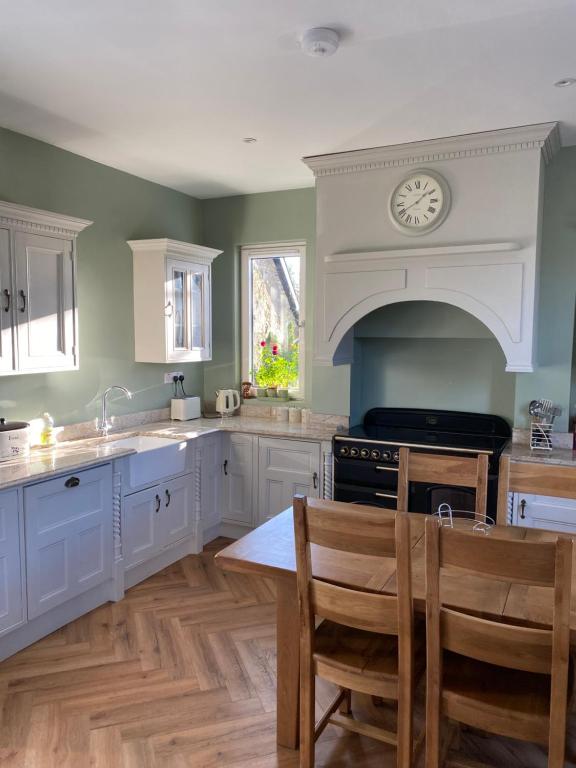 a kitchen with white cabinets and a clock on the wall at Ballea Farmhouse in Cork