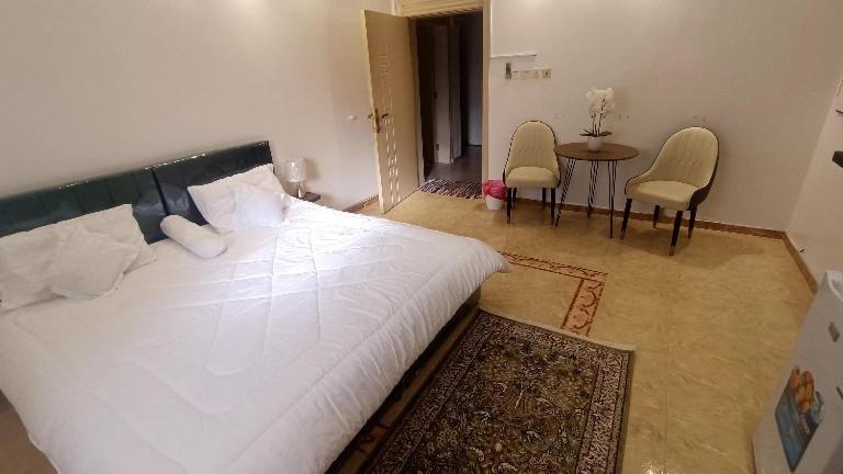 a bedroom with a large bed and a table and chairs at الينبوع الأخضر in Al Madinah